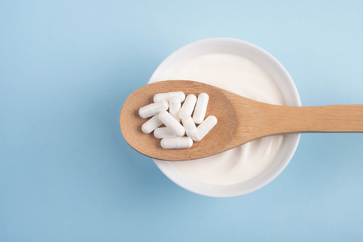 White capsules on spoon on blue background