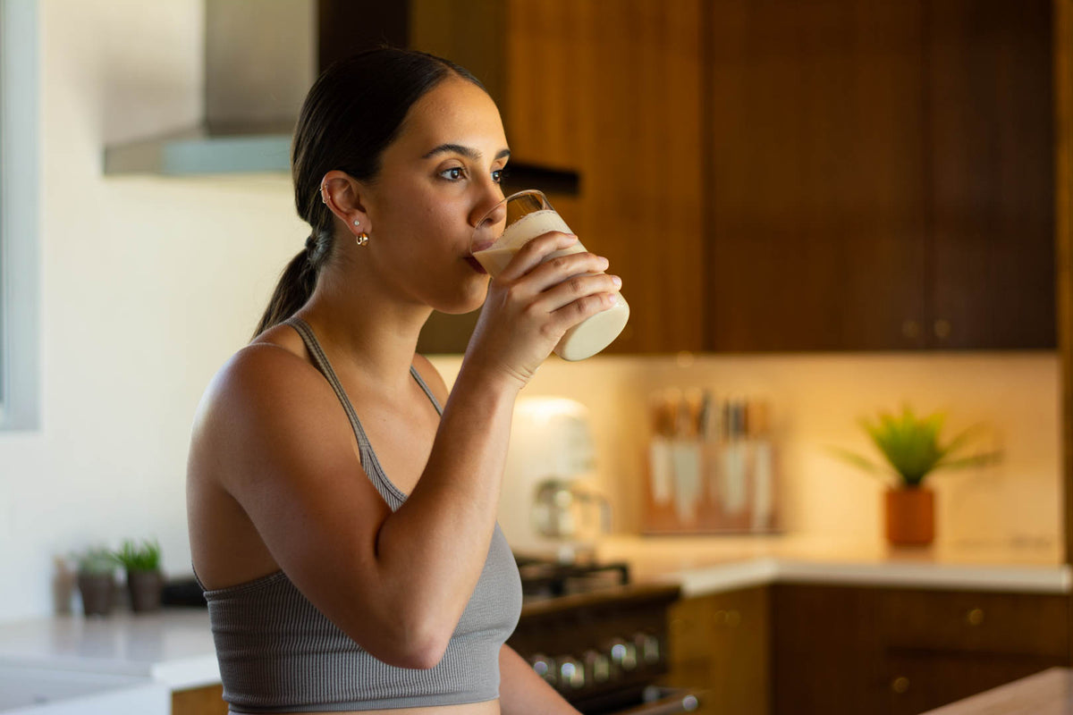 Woman drinking protein shake in kitchen