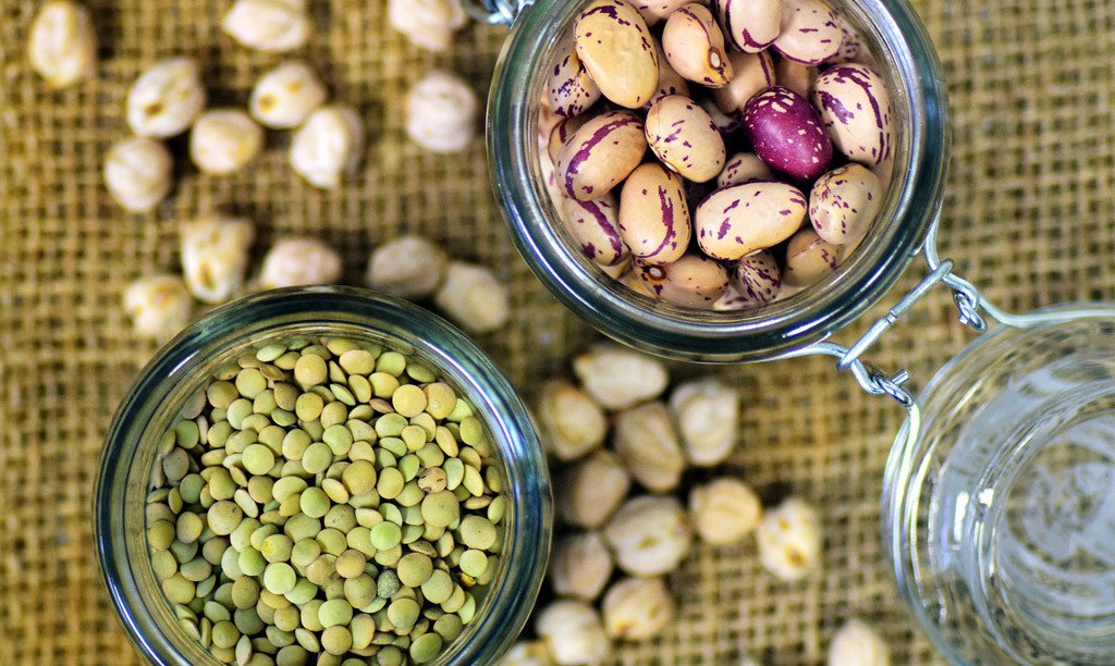 Jars of dried lentils, chickpeas and speckled beans on burlap