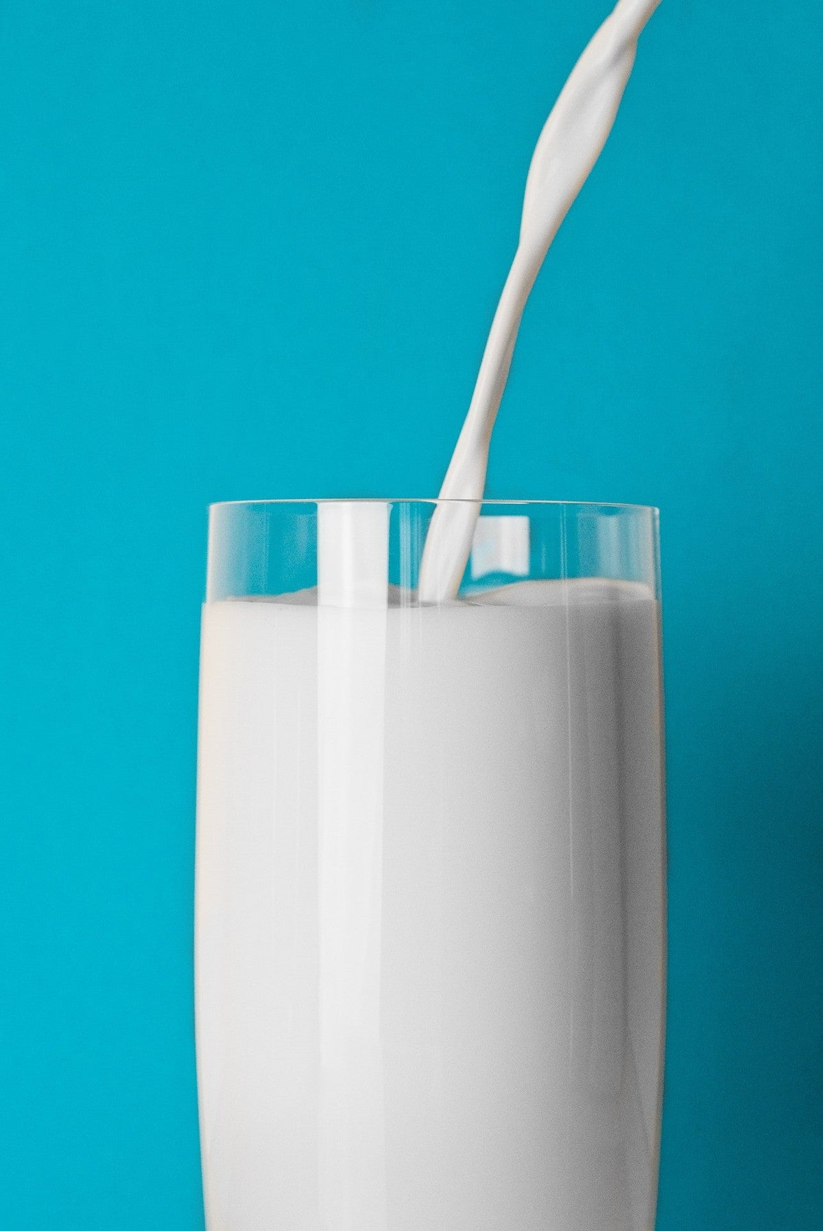 Milk being poured into a glass against a blue background