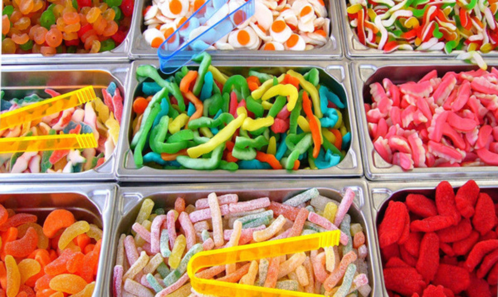 Bins of colorful gummy candies and sour worms at a pick-and-mix candy stand