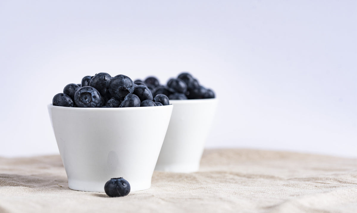 Two white bowls of fresh blueberries