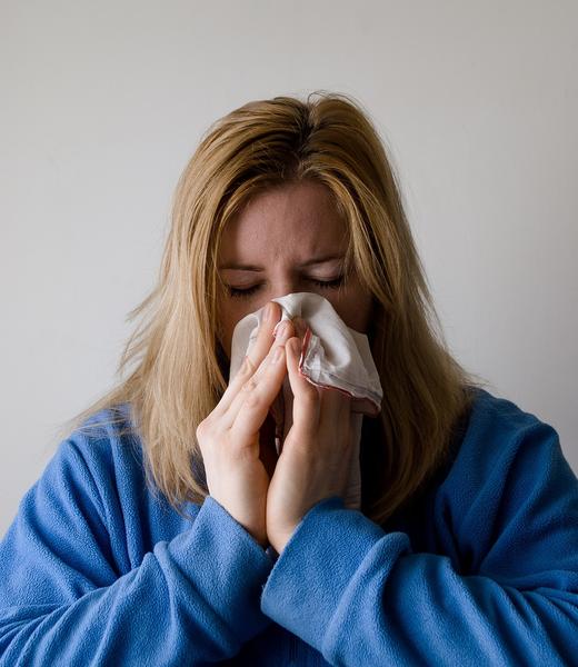 Woman sick in bed with a cold, wrapped in a blanket