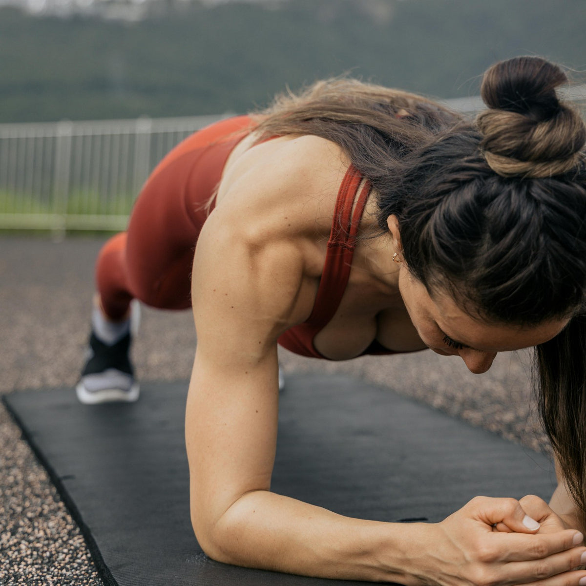 A woman holding a forearm plank on an outdoor mat